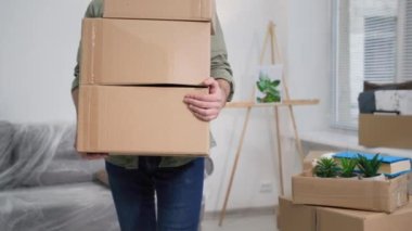 Mülk satın almak, genç adam eşyaları kutularda taşırken mobilyaların arka planına taşınmak, yakın plan