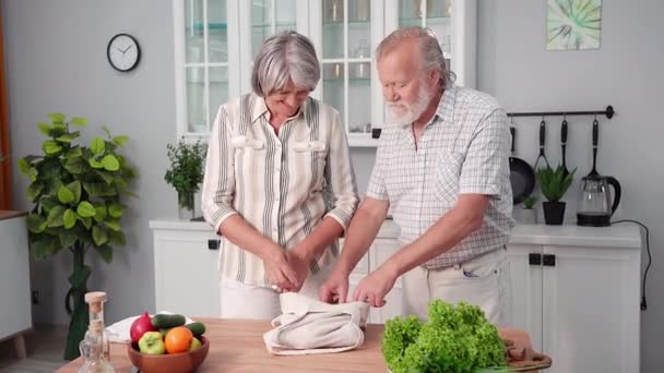 漂亮的退休人员过着健康的生活 从自家厨房桌子上的生态袋里拿出新鲜健康的蔬菜 — 图库视频影像