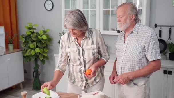 食事や高齢者は台所に立ち健康的な野菜をエコ食料品袋から取り出し — ストック動画