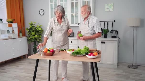 老人和他的妻子一边在厨房里准备一顿健康的早餐 一边在厨房里准备新鲜蔬菜和香草 一边玩得很开心 — 图库视频影像