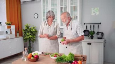 Gülümseyen yaşlı erkek ve kadınların portreleri. Birlikte eğleniyorlar. Bahçeden toplanmış taze sebze salatası hazırlıyorlar.