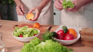 Sağlıklı atıştırmalıklar, yaşlı eşler mutfakta salata hazırlamak için sağlıklı sebzeler kesiyorlar.