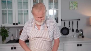 Yaşlı eşler yıldönümünü kutluyor, yaşlı adam romantik bir akşam yemeği hazırlıyor, yaşlı çekici kadın mutfakta kocasının arka planını pişirirken şarap içiyor, gülümsüyor ve kameraya bakıyor.