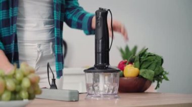 Genç ev hanımı modern elektrikli meyve suyu blendırını masaya takıyor, yakın plan.