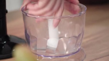 Kadın el blenderi smoothie yapmak için birleştirir, bıçakları masaya yerleştirir, yakın plan.