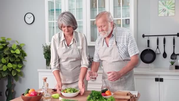 健康饮食亲爱的老夫妇照顾健康 喝凉水 吃新鲜蔬菜沙拉 微笑着看着相机 — 图库视频影像