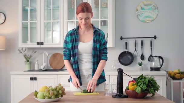适当的营养 年轻女人站在厨房饭桌边切新鲜黄瓜 准备蔬菜沙司 — 图库视频影像