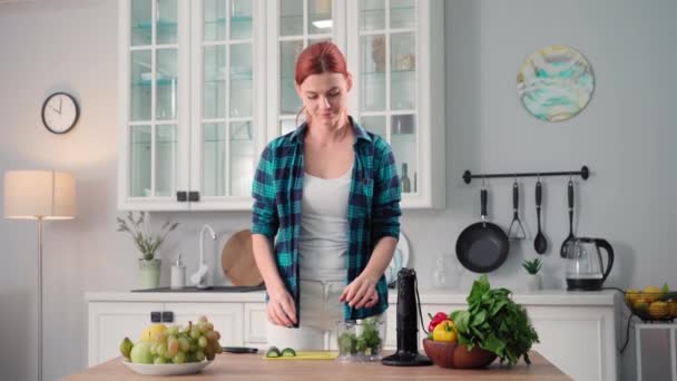 一个女人站在厨房的餐桌前 用新鲜蔬菜和沙拉在搅拌机里画出一个女人的肖像 观察她的营养 — 图库视频影像