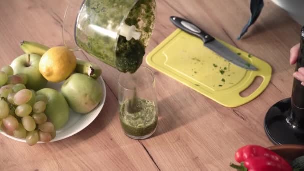 緑のスムージー 若い女性は食事中で テーブルの上のガラスにミキサーから刻んだ野菜やレタスの葉を注ぎ クローズアップ — ストック動画