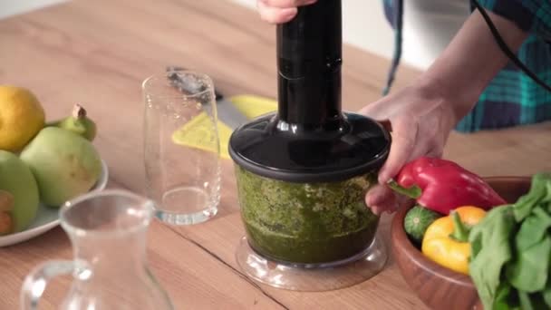 若い女性は体重を監視し 台所のテーブルの上に電気ミキサーでガラスに刻んだ野菜のカクテルを注ぐ クローズアップ — ストック動画