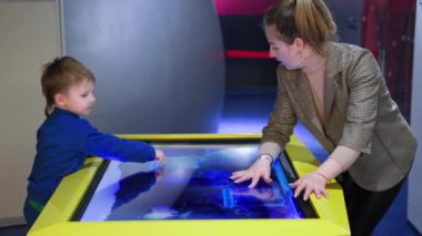 Modern eğitim, mutlu anne ve oğul elektronik dünya haritası okuyorlar, ellerini dokunmatik pedin üzerinde tutuyorlar ve parmaklarını ekranda gezdiriyorlar.