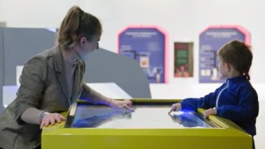 Eğitim teknolojisi, çekici kadın ebeveyn ve küçük çocuk parmaklarını kapalı alanda elektronik harita çalışırken ekranda gezdiriyorlar.