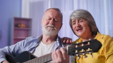 Sevimli yaşlı karı koca gitar çalıyor ve aile akşamını paylaşırken şarkı söylüyorlar.