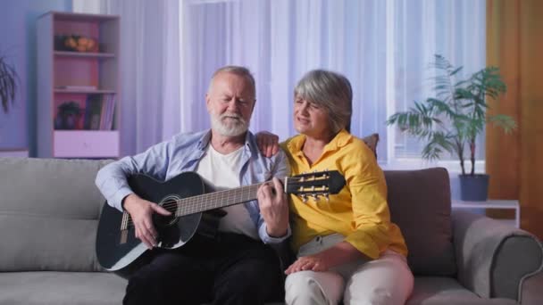 上了年纪的家庭喜欢在一起弹吉他 边唱歌边在家里放松地坐在沙发上 — 图库视频影像