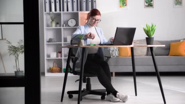 Молода Жінка Окулярах Працює Віддалено Роблячи Нотатки Блокноті Друкуючи Ноутбуці — стокове відео