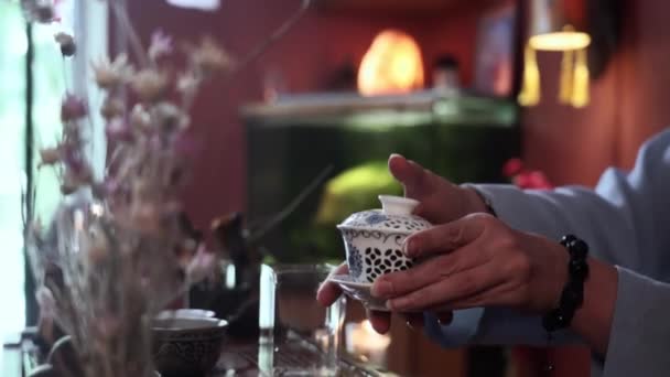 女性の茶人がお湯を注ぎ プーアル茶の花びらを入れて居心地の良い部屋でお茶の儀式を行い クローズアップ — ストック動画