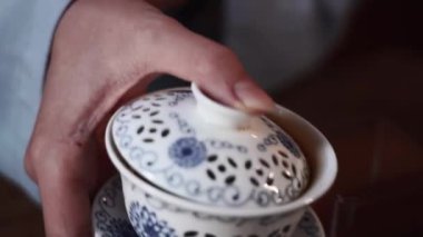 Elinde kase olan kadın çay seremonisi sırasında sıcak çay koyar, yakın plan.