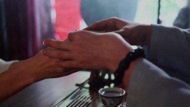 Çekici kadın bir çay seremonisi yapar ve bir kadına el ele verir, yakın plan.