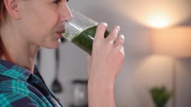 Moda diyeti, taze sebzelerden yeşil smoothie içen çekici genç bir kadın, yakın plan.
