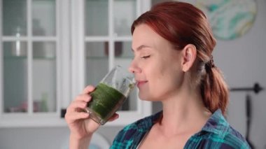 Elinde bir bardak ezilmiş sebze suyu tutan genç bir kadının portresi. Bir yudum alıp gülümsüyor ve kameraya bakıyor.