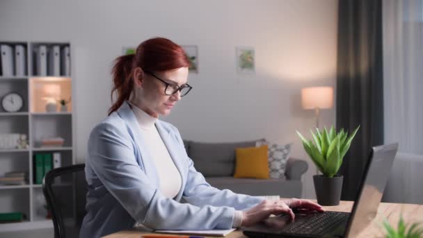 戴眼镜的年轻女经理在电脑前工作 并在总公司的笔记本上记笔记 — 图库视频影像