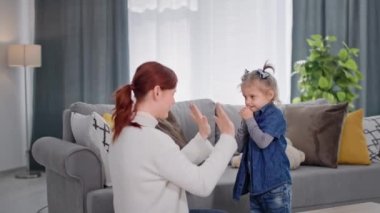 İlgili ebeveyn, çocukların rahat odalarında motor becerilerini geliştiren çocuk oyunları oynayan gülümseyen kızlarıyla eğleniyor.