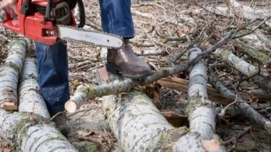 Yaşlı adam oduncu olarak çalışıyor ve elektrikli testere kullanarak yakacak odun bulmak için caddeyi ikiye ayırıyor.
