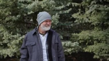 Elinde baltayla gülümseyen yaşlı bir adamın portresi ladin arka planında odun kıracak, gülümseyecek ve kameraya bakacak.