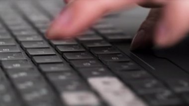 Bilgisayardaki klavyede mesaj ya da metin yazan genç bir kadın, parmakları yakın plan