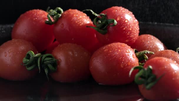 맛있는 토마토를 어두운 배경에 뿌리고 클로즈업 — 비디오
