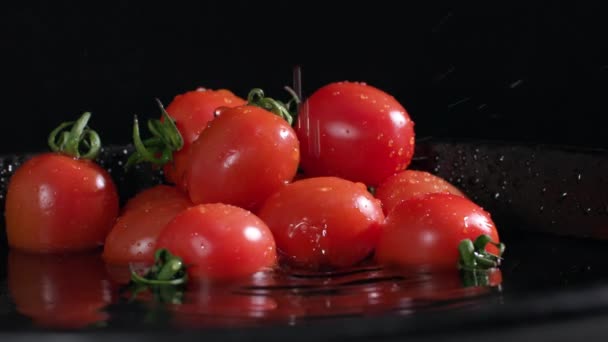 食欲をそそる熟したトマトは暗い背景の水でプレートに一握りにあり クローズアップ — ストック動画