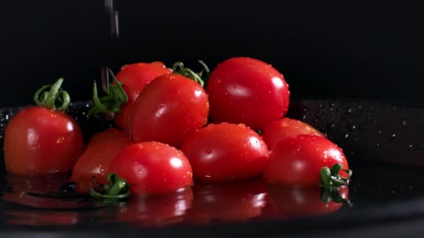 野菜の収穫 一握りの熟したトマトは暗いプレートの上にあり 背景に水が飛び散っています クローズアップ — ストック動画