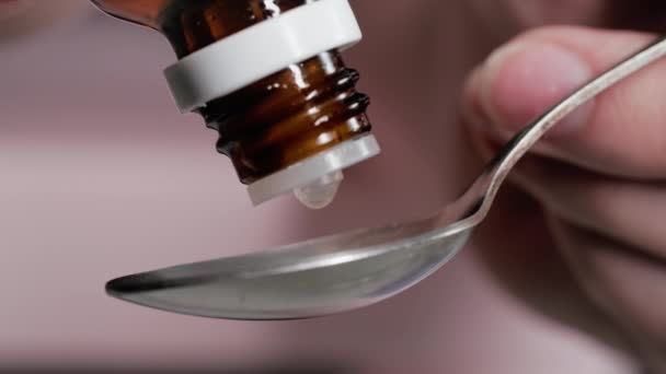 用药时 女人用手将药滴从瓶子里滴入汤匙 以缓解压力 — 图库视频影像