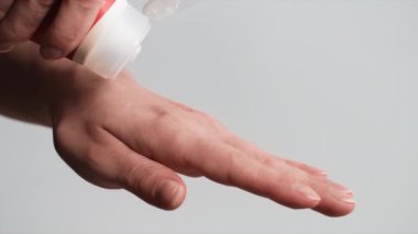 El bakımı, genç bir kadın avuçlarına nemlendirici sürüyor ve arka planda hafifçe okşuyor, yakın plan.