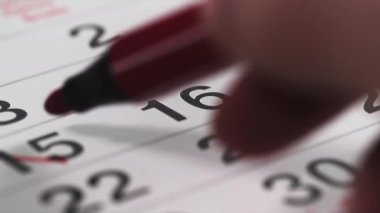 Etkinlik, kadın el işaretleri takvim üzerinde kırmızı kalemle tarih, numarayı karalar ve masa başına keçeli kalem koyar