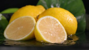 Olgun, sağlıklı bir limon dilimi koyu bir arka planda meyvelere düşer. Yakın plan.