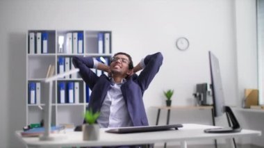 Neşeli genç Afro-Amerikan çağrı merkezi çalışanı, iş yerinde otururken ellerini başının arkasına koyarak işe başlıyor.
