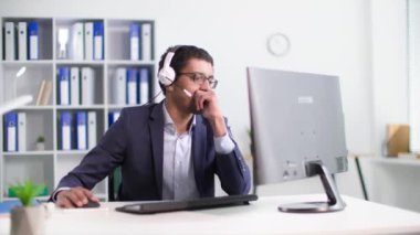 Çağrı merkezi, gözlüklü genç Afro-Amerikan erkek yönetici ofiste siyad müşterisiyle kulaklık ve mikrofon kullanarak konuşuyor.