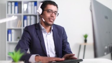 Genç siyahi adam çağrı merkezinde teknik destek bölümünde çalışıyor ve ofiste otururken bir müşteriye kulaklığı mikrofonda kullanmasını tavsiye ediyor.