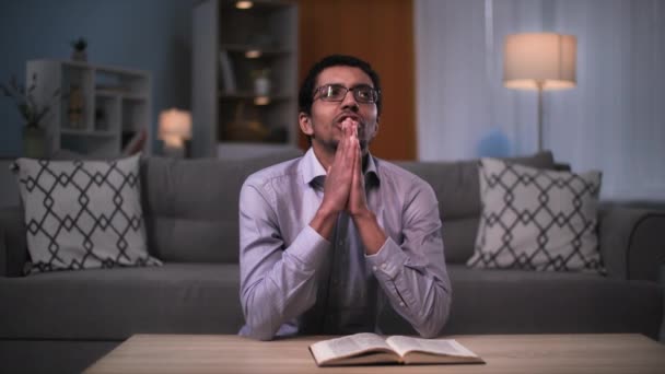 愛と信仰を胸に眼鏡をかけた黒人が寝る前に膝の上で神に祈る — ストック動画
