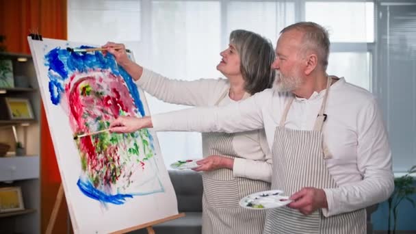 재능있는 은퇴자 노인과 여성은 캔버스에 브러시와 페인트로 그림을 그립니다 — 비디오