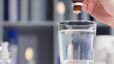 Kadın sinir sistemi için damla damlatıyor ya da basıncı şeffaf su bardağına boşaltıyor, yakın plan.