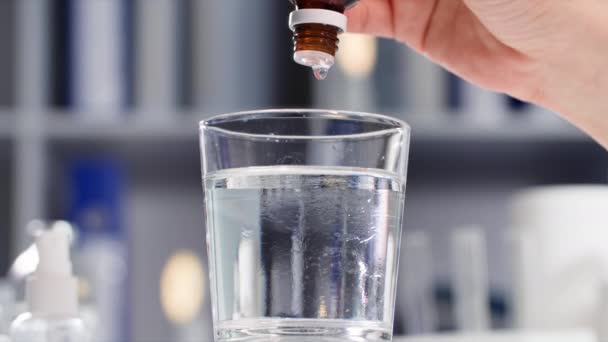 ヘルスケア 女性は圧力を正常化するために水の透明なガラスにディスペンサーとボトルから滴下 クローズアップ — ストック動画