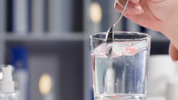 女人用勺子在透明的水杯里搅拌药品 并制定了相应的计划 — 图库视频影像