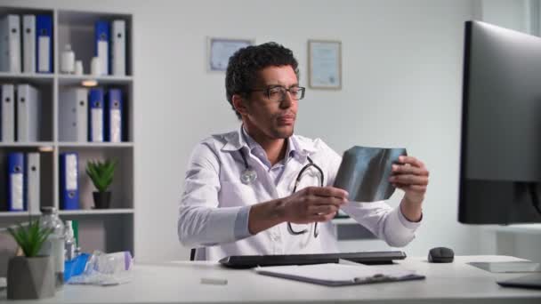 Врач Черный Мужчина Осматривает Рентген Сидя Компьютером Медицинском Кабинете — стоковое видео