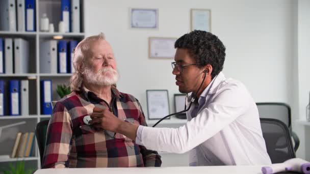 非洲裔美国医生在医务室用留声机检查老年病人 — 图库视频影像