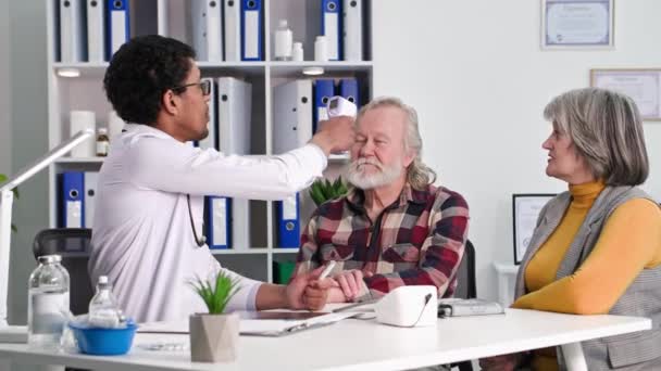 Siyah Erkek Doktor Yaşlı Hastaları Muayene Ediyor Sıcaklığı Sağlık Odasındaki — Stok video