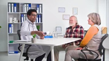 Doktor randevusundaki yaşlı evli çift, Afrikalı Amerikalı doktor yaşlı bir adam ve kadının sağlık durumlarına danışmanlık yapıyor.