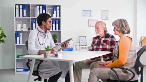 Orvosi Konzultáció Fekete Orvos Vizsgál Egy Idős Pár Kórházi Irodában — Stock videók