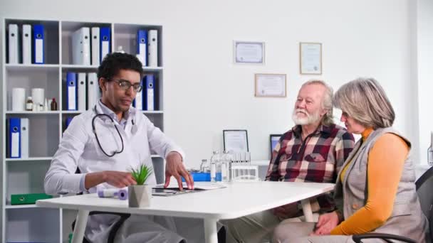 Idős Házaspár Konzultáció Egy Fekete Orvos Nézi Röntgen Miközben Kórházi — Stock videók